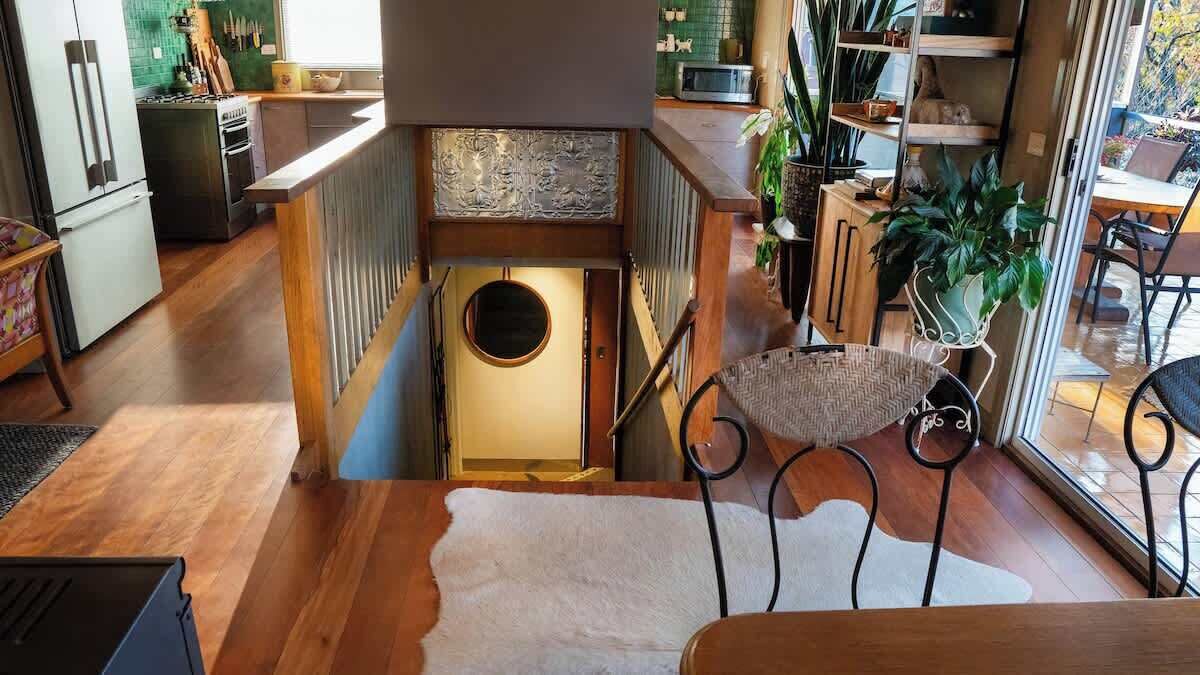 Eine Küche mit einer Holztreppe, einer runden Tür und einem Essbereich mit Tisch und Stühlen.