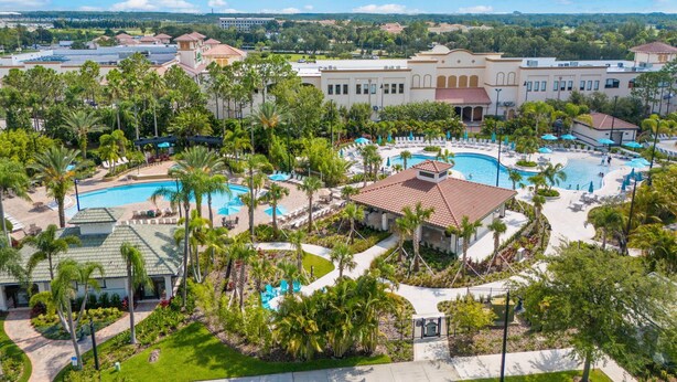 Een resort met meerdere zwembaden, palmbomen en een groot gebouw met een rood dak.