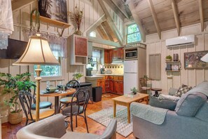 A spacious living area with a dining table, chairs, a sofa, and a kitchen in the background.