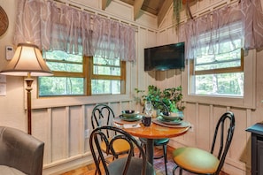 A dining area with a round table, chairs, a lamp, and a television mounted on the wall. - Back on Market! Creekside Studio Near Table Rock (Table Rock)
