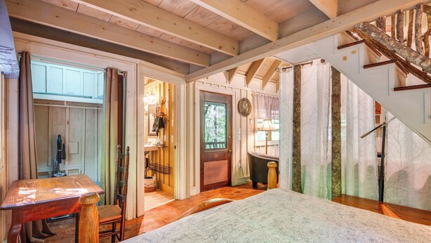 A room with a bed, wooden furniture, a staircase, and a door leading to another room. - Back on Market! Creekside Cottage Near Table Rock (Table Rock)