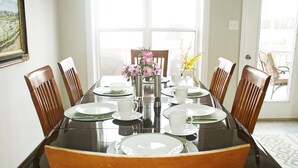 Une table à manger dressée avec des assiettes, des tasses et un vase rempli de fleurs.