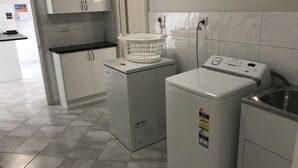 A laundry area with two front-loading washing machines, a small sink, and a countertop with a basket. - Beachside & Jetty View Apartment 6 ( Captains Apartment)  (Streaky Bay)