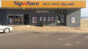 A SipnSave Beck Bros Cellars store with a clear entrance, promotional posters on the windows, and a parking lot in front. - Beachside & Jetty View Apartment 6 ( Captains Apartment)  (Streaky Bay)