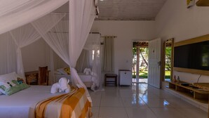 A spacious bedroom with a bed, a TV, and a view of the outdoors. - Pousada Recanto Trancoso (Porto Seguro)
