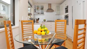 Una cocina moderna con armarios blancos, una mesa de comedor de vidrio y sillas de madera.