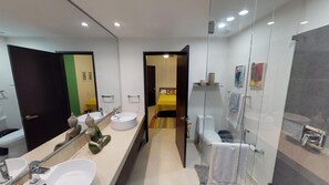 A modern bathroom with dual sinks, a large mirror, and a glass shower enclosure.
