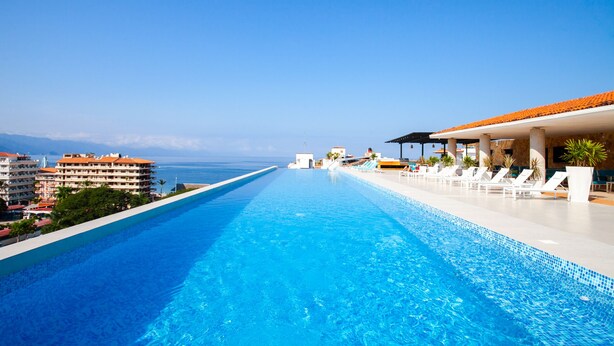 Una piscina larga con sillas de descanso y vistas al océano.