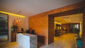 Una moderna zona de recepción con mostrador de mármol, paredes de ladrillo y suelo de madera.
