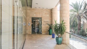 A hotel lobby with a stone wall, a glass door entrance, and potted plants.