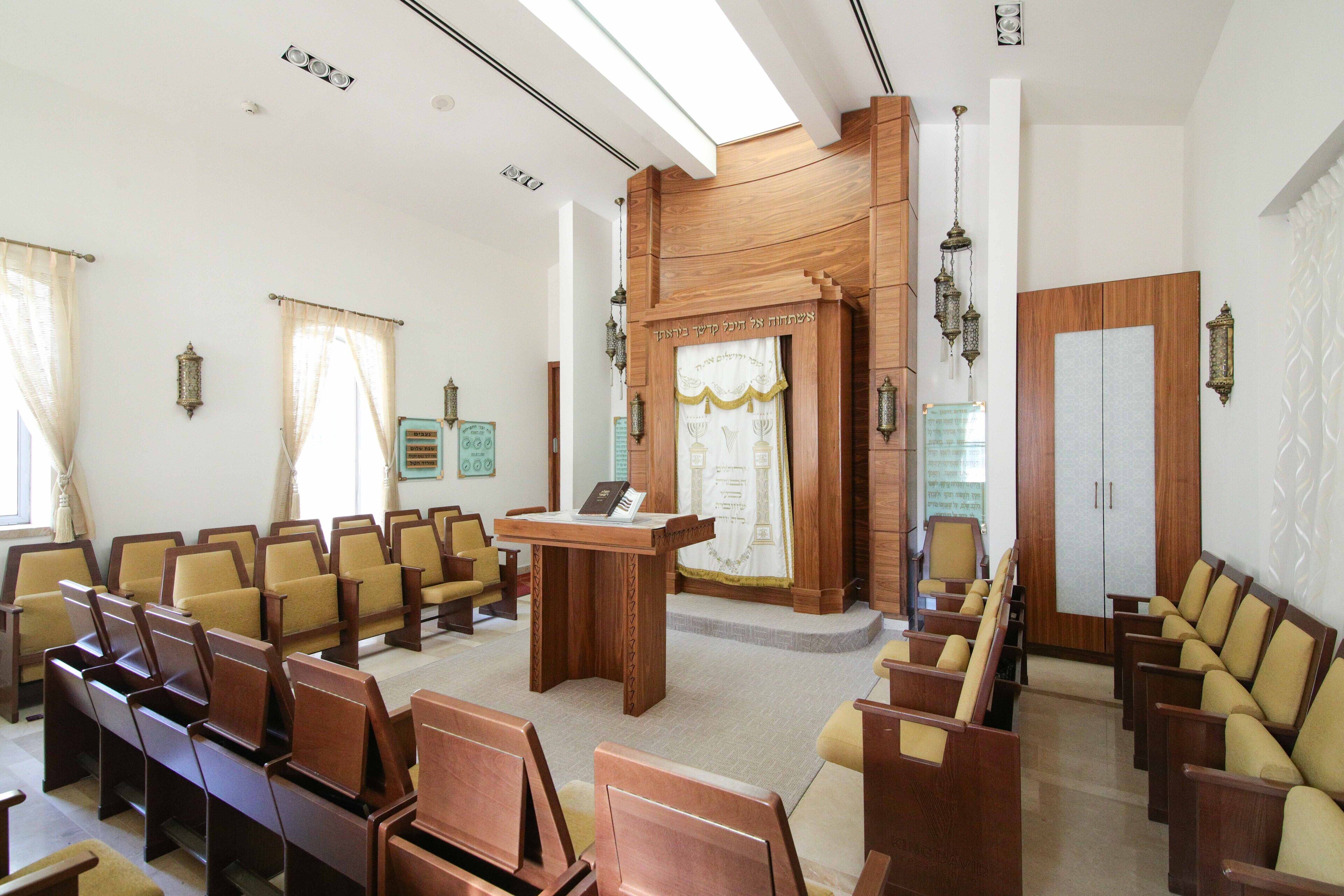 Un salón de conferencias con filas de sillas de madera, un atril y faroles decorativos.