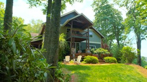 A two-story house with a balcony, surrounded by trees and a grassy lawn. - Gated Luxury Lodge - Hot Tub, Mountain Views, Stunning Gardens, Secluded (Franklin)