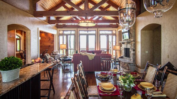 A spacious dining area with a wooden ceiling, large windows, and a stone fireplace. - Gated Luxury Lodge - Hot Tub, Mountain Views, Stunning Gardens, Secluded (Franklin)