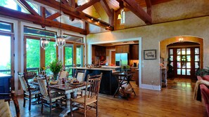 A spacious kitchen with wooden beams, a dining area with wicker chairs, and a view of the outdoors. - Gated Luxury Lodge - Hot Tub, Mountain Views, Stunning Gardens, Secluded (Franklin)