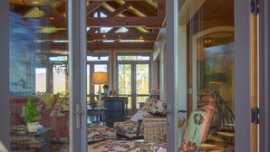 A spacious room with a high ceiling, wooden beams, and large sliding glass doors leading to an outdoor area. - Gated Luxury Lodge - Hot Tub, Mountain Views, Stunning Gardens, Secluded (Franklin)