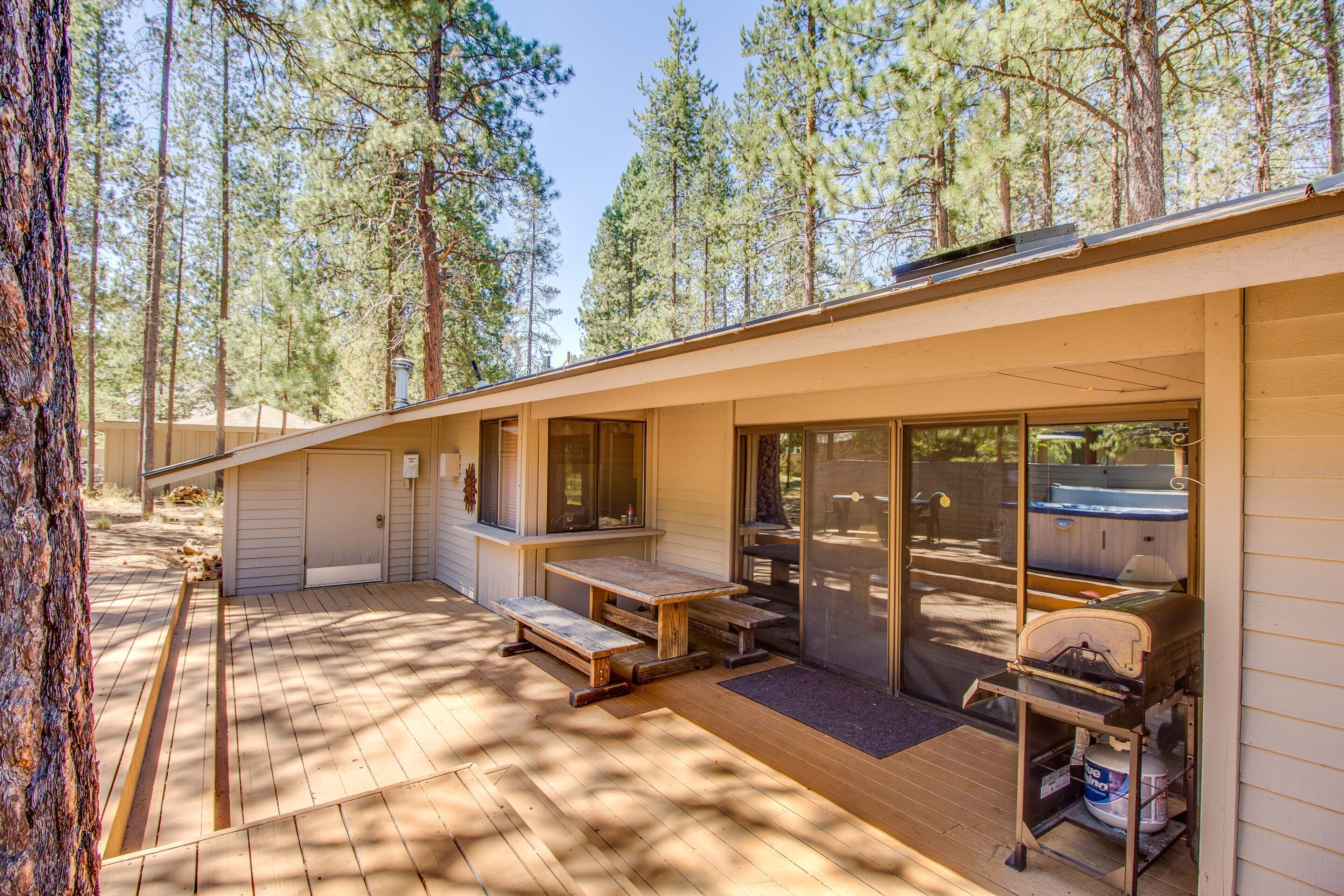A cabin with a deck, picnic table, and barbecue grill.