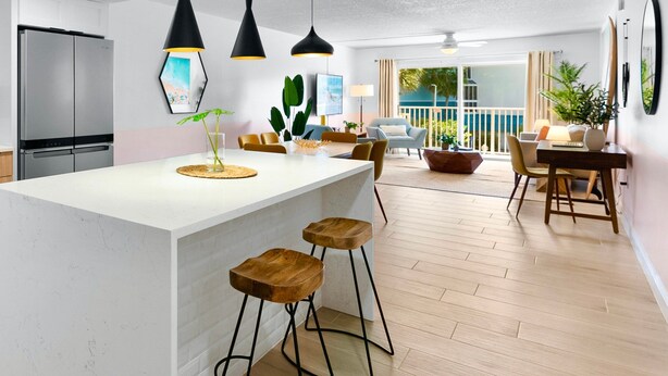 Een moderne keuken met een centraal eiland, barstoelen, hanglampen en een eethoek met uitzicht op de omgeving.