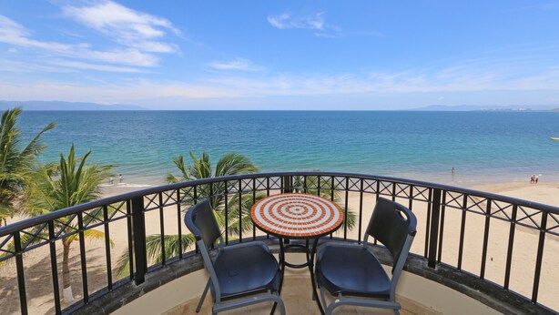 A balcony with a table and chairs overlooking a beach. - 😍ROMANTIC GETAWAY😍AMAZING OCEAN VIEWS -HOP, SKIP & JUMP TO THE BEACH -GR8 POOL (Puerto Vallarta)