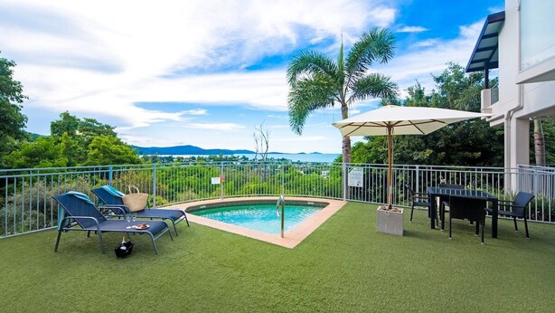 A backyard with a swimming pool, lounge chairs, a table, and a dining area. - Oscar's View - Airlie Beach (Airlie Beach)