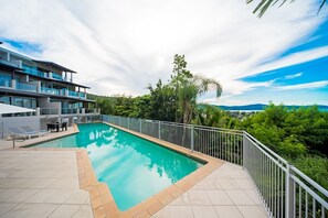 Ein Pool mit Blick auf ein mehrstöckiges Gebäude und umgebende Grünflächen.