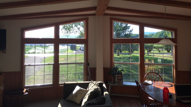 A room with large windows, a sofa, a dining table, and a laptop. - Best of both worlds! Amazing views plus an easy walk into town! (New Paltz)