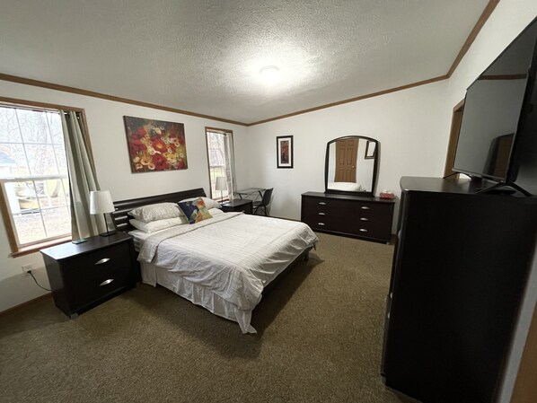 A bedroom with a bed, a dresser, a desk, a chair, a mirror, and a television. - Best of both worlds! Amazing views plus an easy walk into town! (New Paltz)