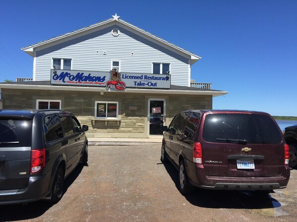 A building with a sign for 'McMahons Licensed Restaurant Take-Out' and two parked vehicles in front.
