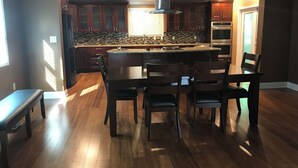 Una cocina moderna con armarios de madera, una isla central y un comedor con banco y sillas.