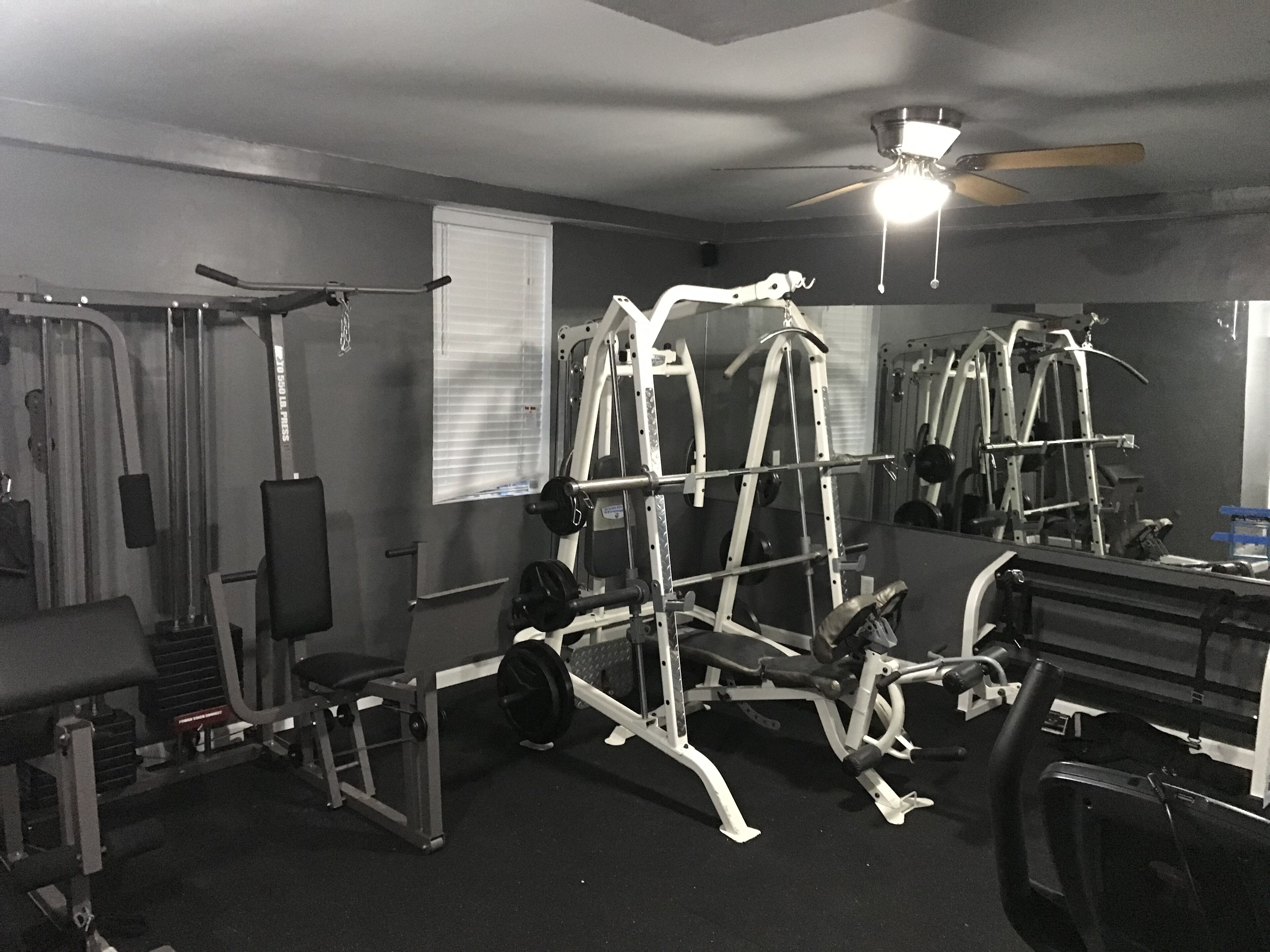 Un gimnasio con diversos equipos de ejercicio, incluyendo máquinas de pesas y bancos.