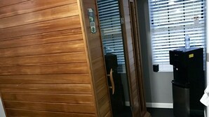 Un pasillo con paneles de madera, un dispensador de agua y un contenedor de basura.