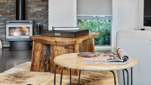 A cozy living room with a fireplace, a round wooden table, and a comfortable sofa.