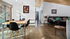 A modern living space with a dining area, a sofa set, and artwork on the walls.