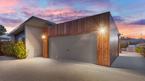 A modern house with a garage door, wooden siding, and a driveway.