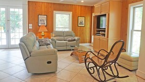 A living room with a sofa, armchair, and a TV stand. - Deetjen Beach House - Near Beach & Bike Trail. North Litchfield Favorite! (Pawleys Island)