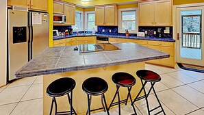 A modern kitchen with a large island, bar stools, and built-in appliances. - Deetjen Beach House - Near Beach & Bike Trail. North Litchfield Favorite! (Pawleys Island)