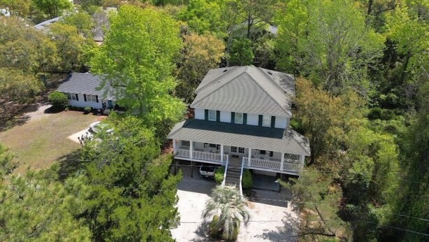 A two-story house with a gabled roof, surrounded by dense greenery and a view of the ocean. - Deetjen Beach House - Near Beach & Bike Trail. North Litchfield Favorite! (Pawleys Island)