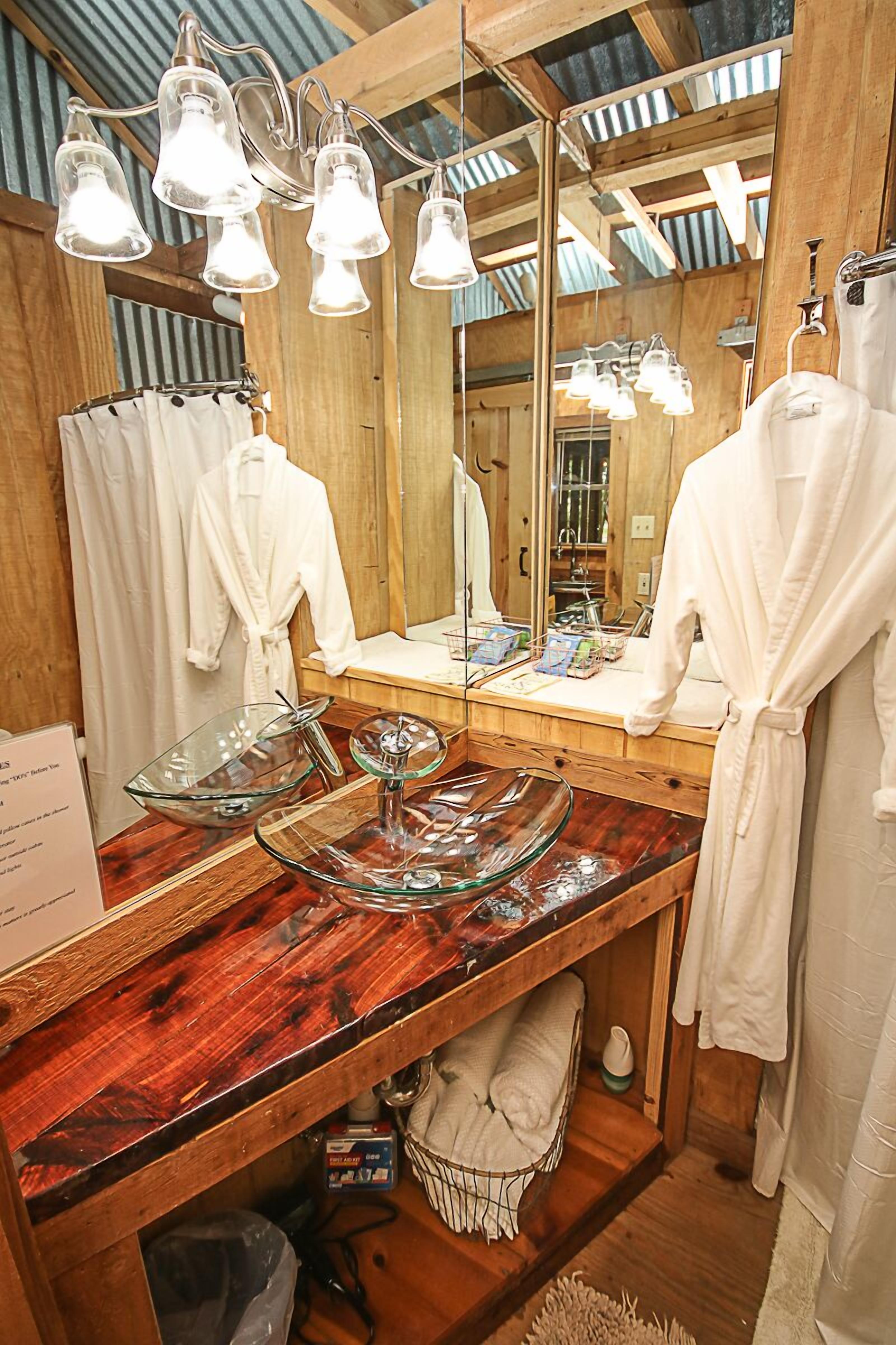 A bathroom with wooden walls, a large mirror, and a vanity with a glass bowl centerpiece.