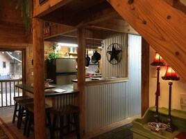 Una cocina rústica con vigas de madera, una barra y un banco verde.