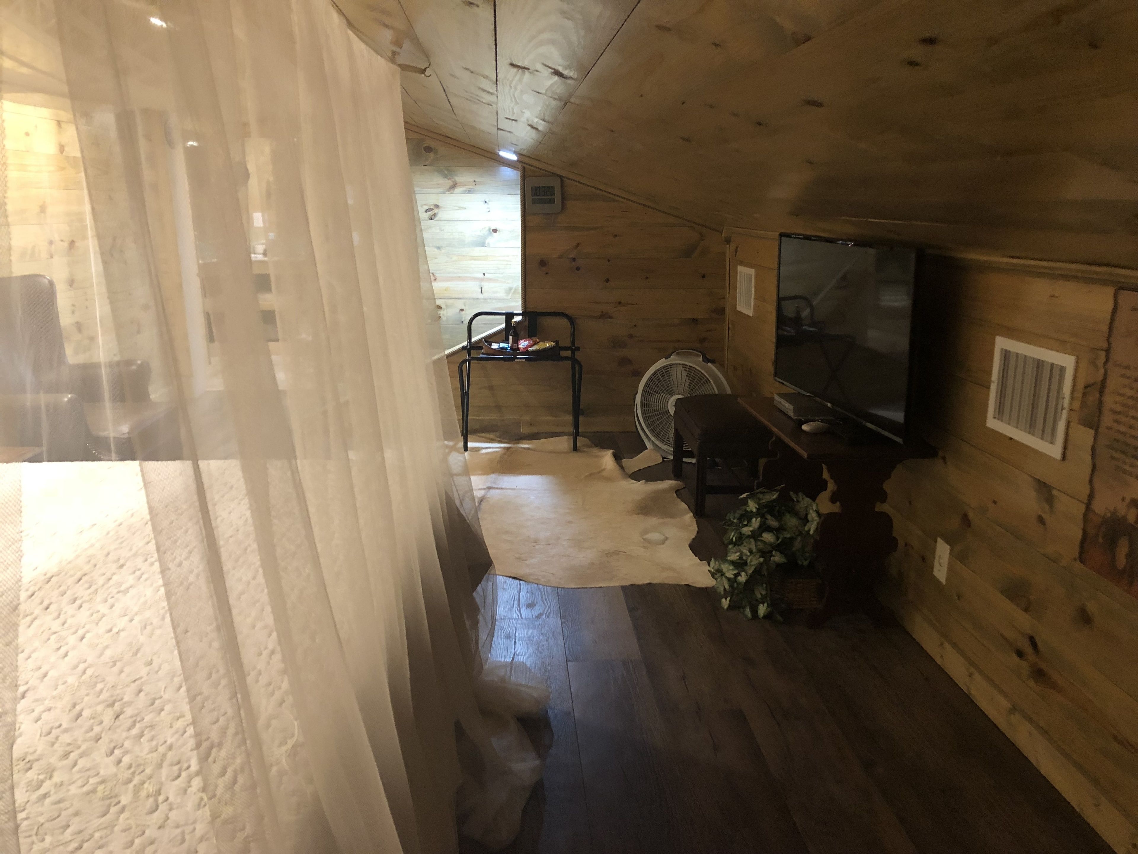 Ein rustikaler Holzblock-Innenraum mit Fernseher, Ventilator und einem kleinen Tisch.