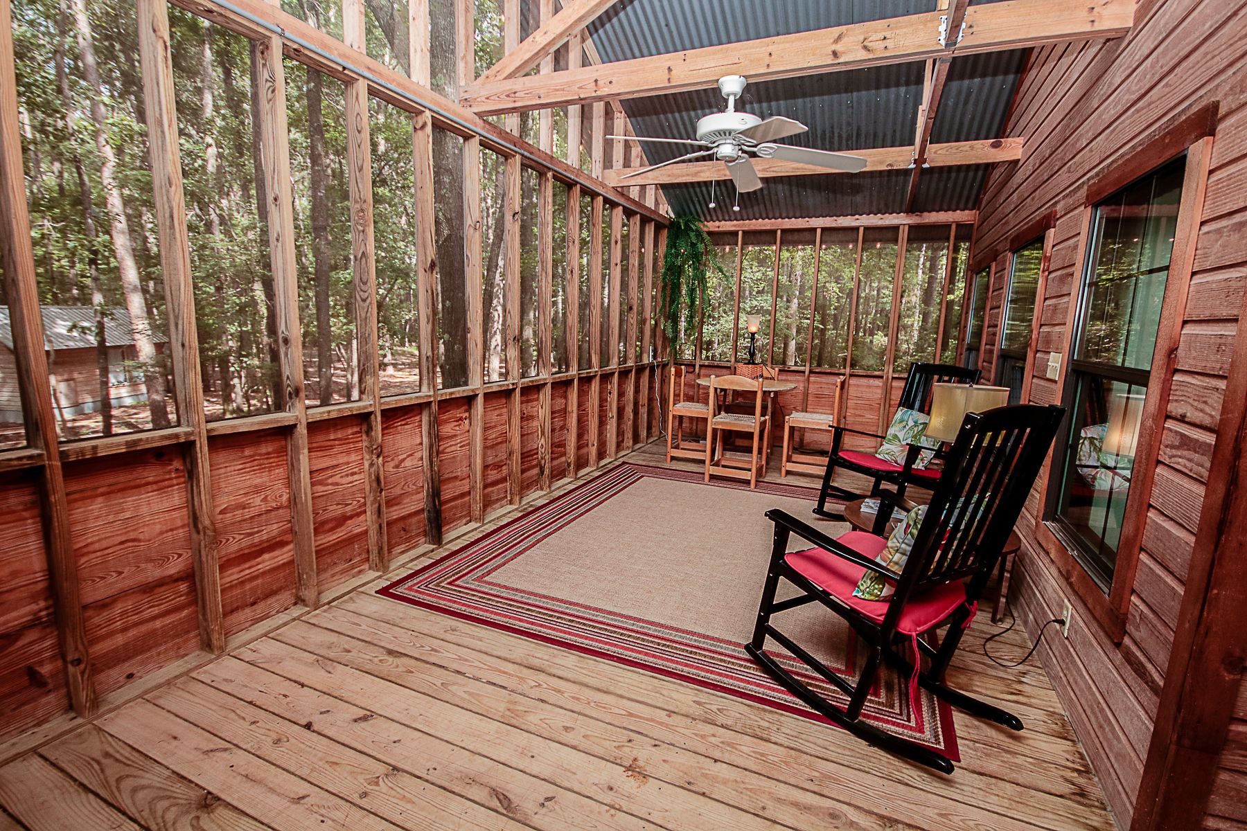 A wooden deck with a ceiling fan, a dining table, and chairs.