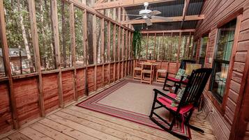 A wooden deck with a ceiling fan, a dining table, and chairs.