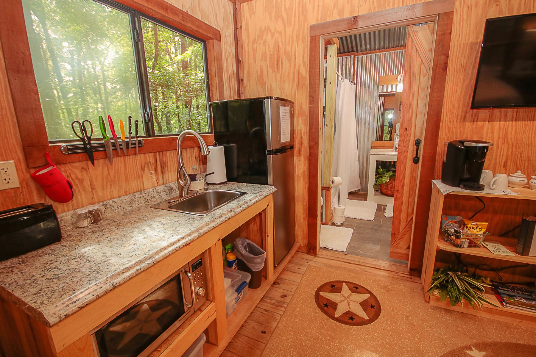A compact kitchen with granite countertops, a stainless steel sink, a built-in microwave, and a refrigerator.