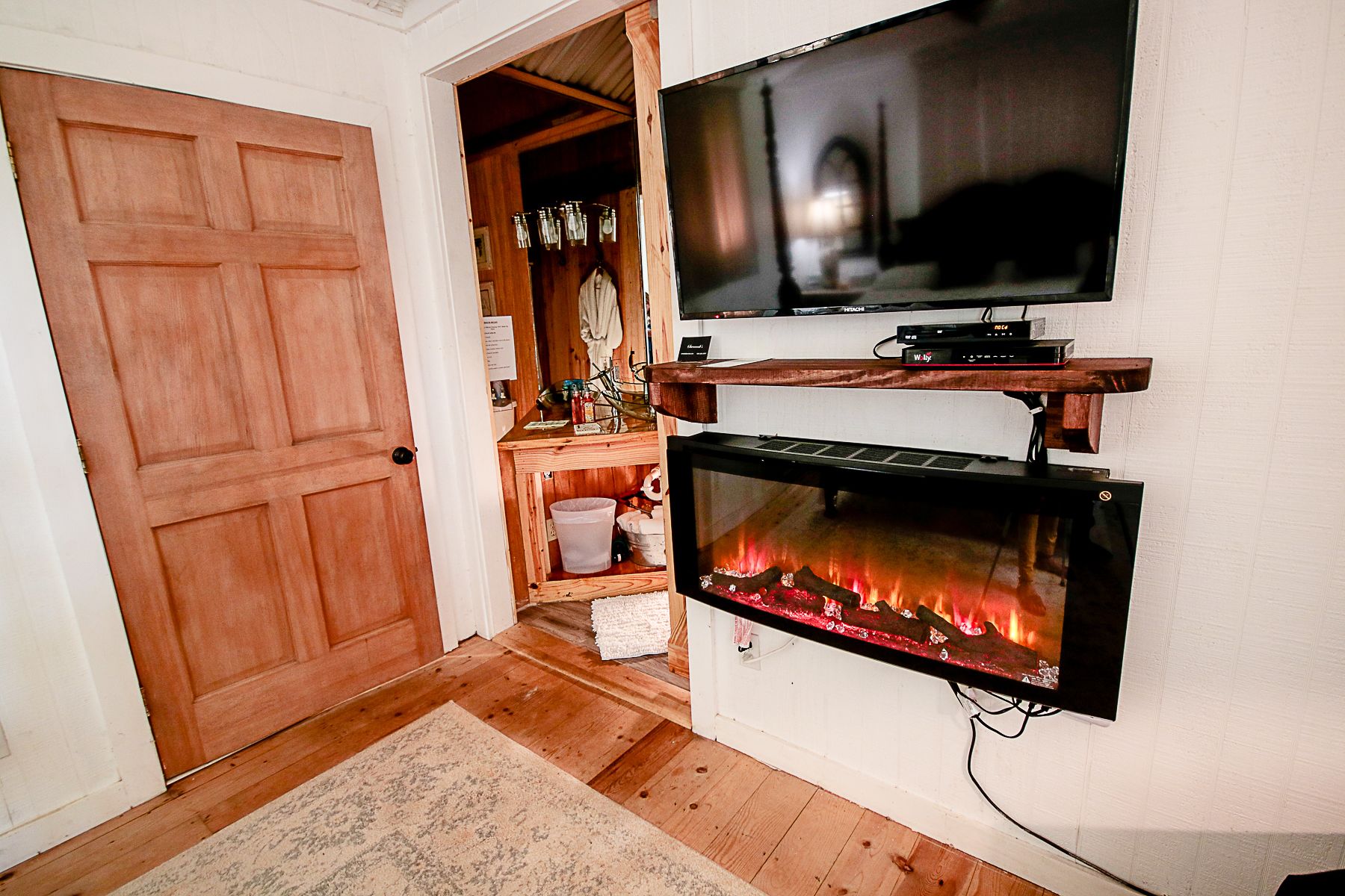 Una sala de estar con chimenea, un televisor montado en la pared y una puerta de madera.