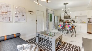 Una sala de estar moderna con una mesa de fútbol de mesa, un sofá y una zona de comedor con sillas coloridas.