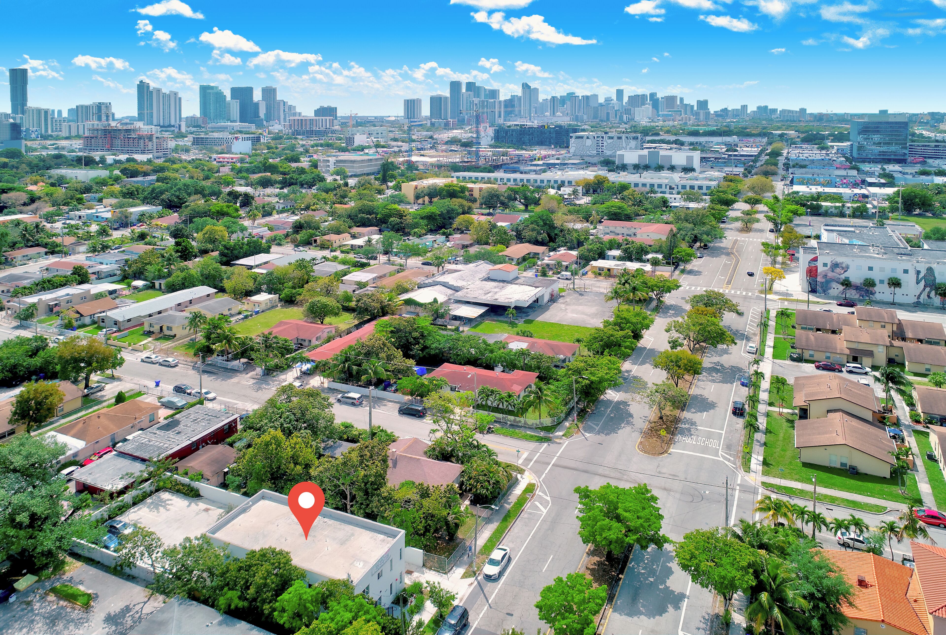 An aerial view of a residential area with houses, streets, and a city skyline in the background.