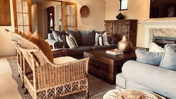 Een woonkamer met een bank, fauteuil, salontafel en een open haard.