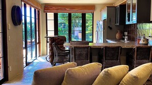 Ein großzügiger Wohnbereich mit einer großen Couch, einem Esstisch mit Stühlen und einer Küchenzeile mit Schränken und einem Kühlschrank.