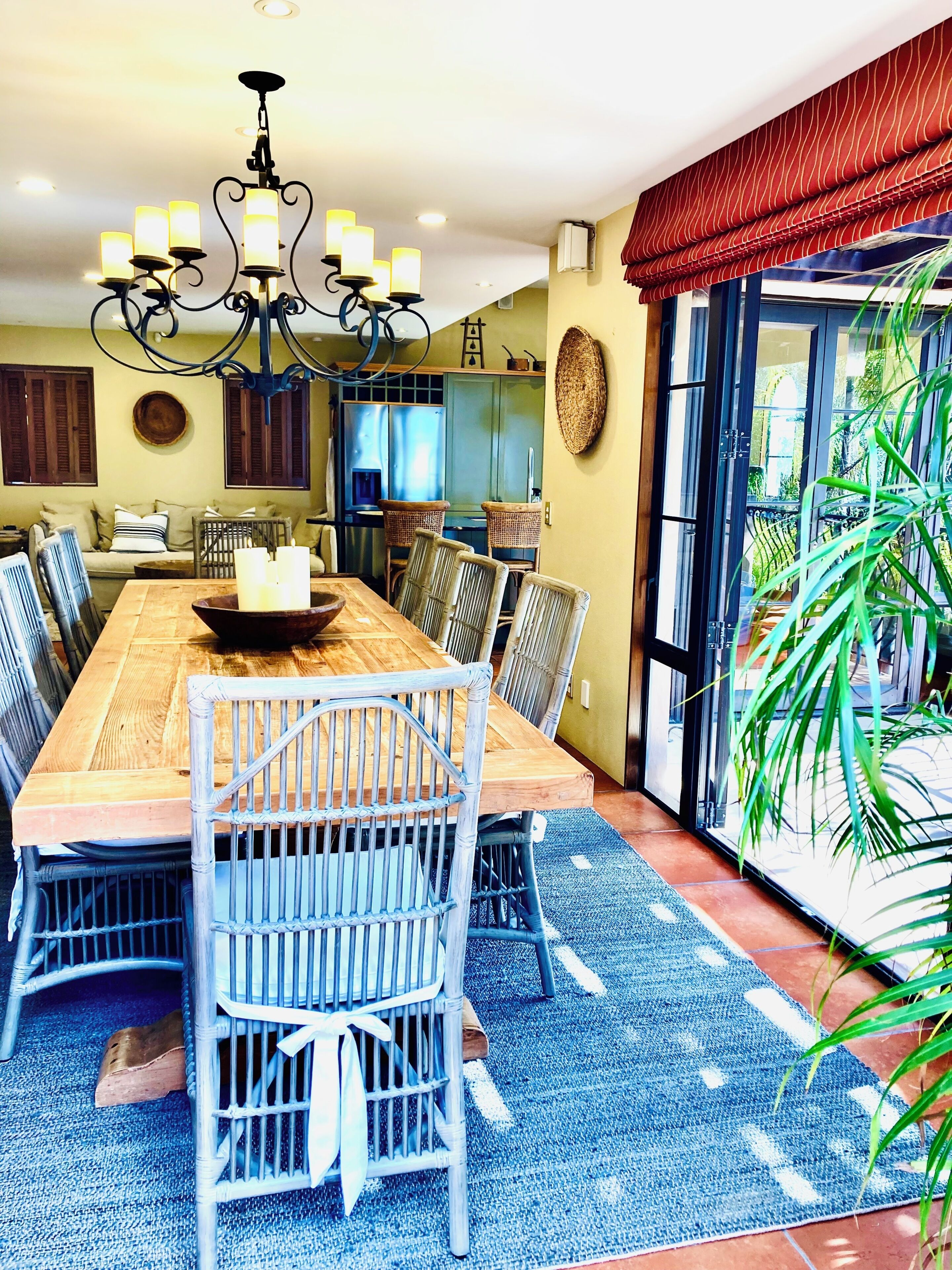Un coin repas avec une table en bois, des chaises en osier et un lustre.