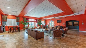 A spacious lobby with a high ceiling, a reception desk, seating areas, and large windows allowing natural light. - Family Friendly 2BR Condo at Oakwater Resort – 1.5 Miles to Disney (Kissimmee)