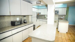 Eine Küche mit weißen Schränken, einer Granit Arbeitsplatte, einem Toaster, einem Mixer und einer Mikrowelle.